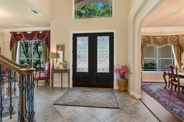 entryway with arched walkways, ornamental molding, baseboards, and french doors