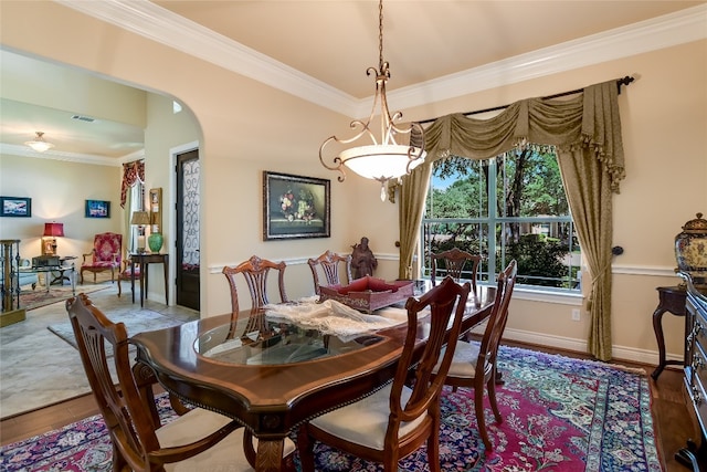 dining area featuring arched walkways, ornamental molding, wood finished floors, and baseboards