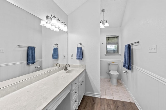 bathroom featuring lofted ceiling, vanity, toilet, a chandelier, and wood finished floors