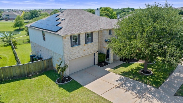 traditional home with stone siding, roof mounted solar panels, driveway, and a shingled roof