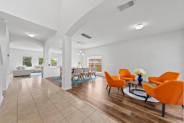 sitting room featuring arched walkways, light wood-style flooring, and baseboards
