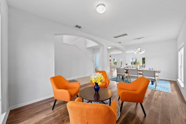 sitting room featuring arched walkways, wood finished floors, baseboards, and a chandelier