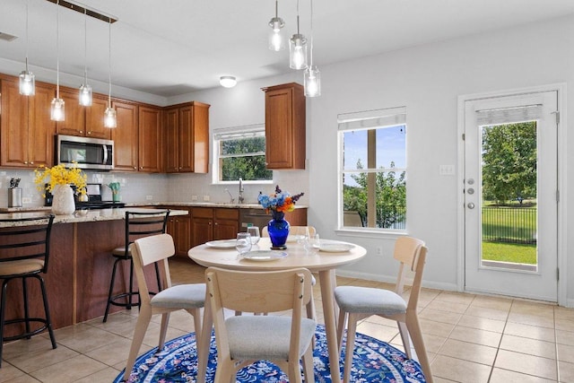 kitchen with stainless steel microwave, light tile patterned floors, backsplash, and hanging light fixtures