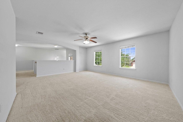 spare room featuring ceiling fan, light carpet, and baseboards