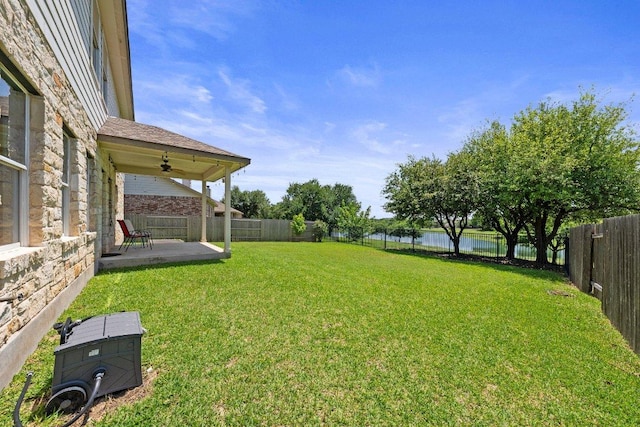 view of yard with a water view, a patio, and a ceiling fan