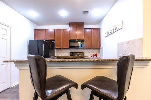 9005 Pin Brush Dr, Austin, TX 78748 - kitchen featuring black appliances, decorative backsplash, a kitchen bar, and stone counters