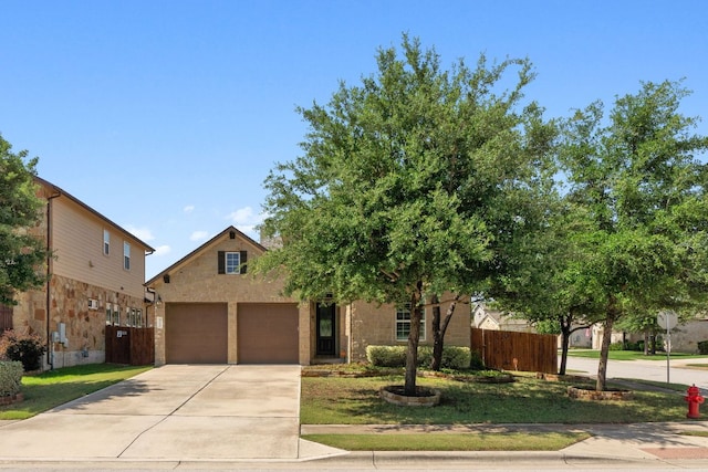 view of front facade featuring driveway, a garage, and fence