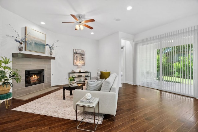living area with ceiling fan, wood finished floors, a tiled fireplace, baseboards, and recessed lighting