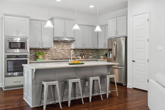 kitchen featuring appliances with stainless steel finishes, light countertops, dark wood finished floors, and recessed lighting