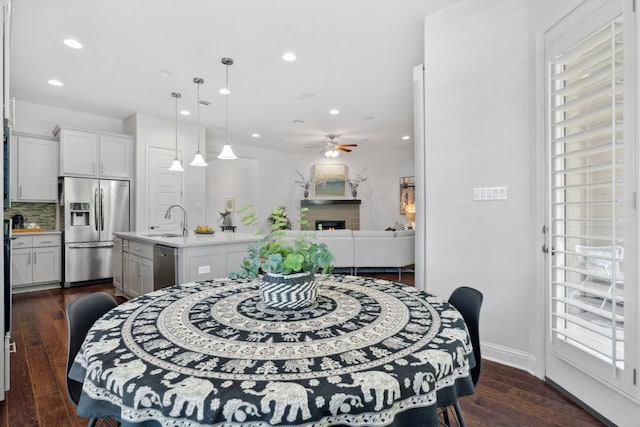 4113 Rainy Creek Ln, Cedar Park, TX 78613 - dining space featuring ceiling fan, recessed lighting, dark wood-type flooring, a lit fireplace, and baseboards