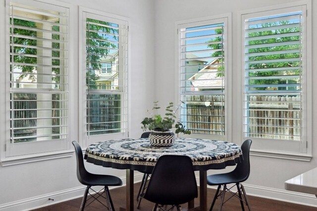 dining area with baseboards, dark wood-type flooring, and healthy amount of natural light