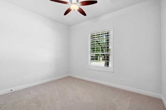 empty room with carpet, a ceiling fan, and baseboards