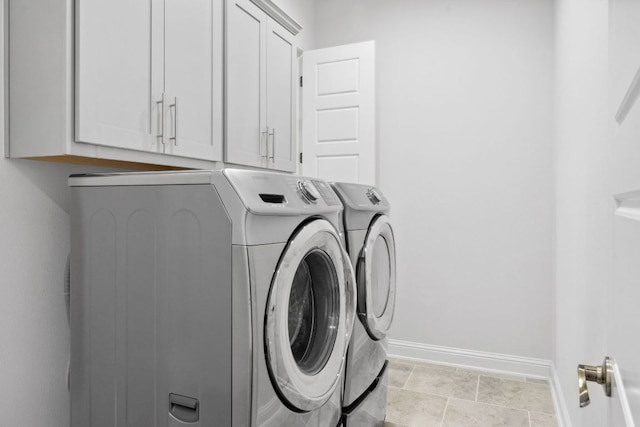 laundry room with washing machine and dryer, cabinet space, and baseboards