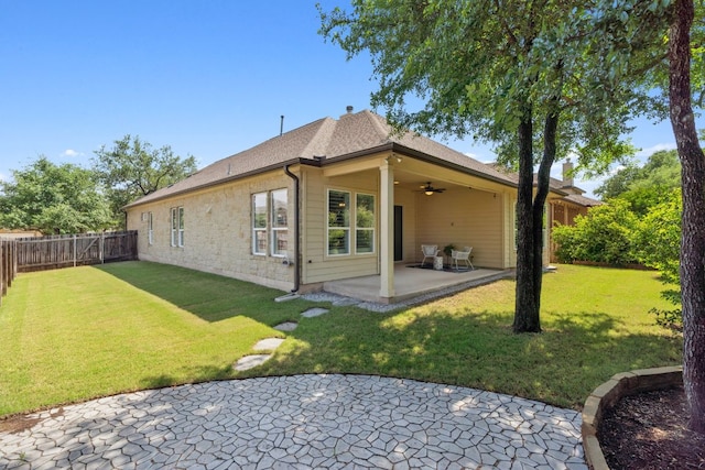 rear view of house featuring a ceiling fan, a patio, stone siding, and roof with shingles