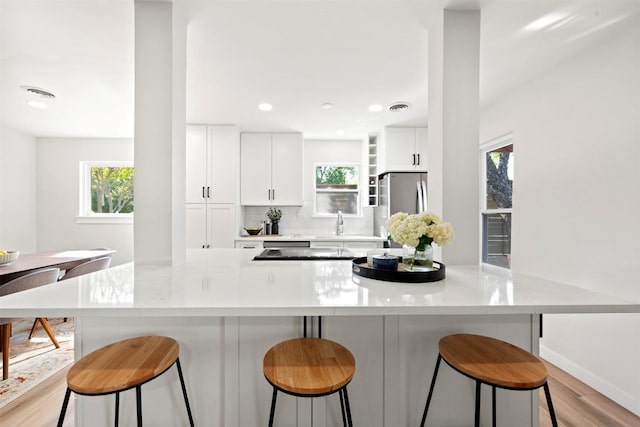 616 Bissonet Ln, Austin, TX 78752 - kitchen with freestanding refrigerator, healthy amount of natural light, light wood-style flooring, white cabinets, and recessed lighting