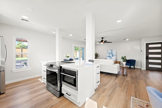 616 Bissonet Ln, Austin, TX 78752 - kitchen featuring stainless steel appliances, plenty of natural light, white cabinets, light wood-type flooring, and recessed lighting