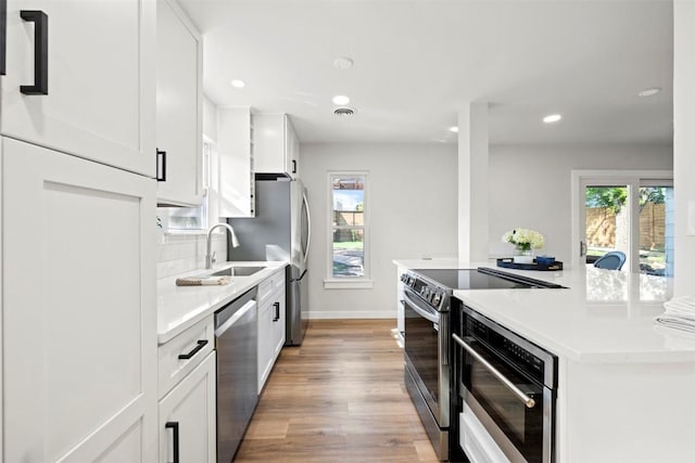616 Bissonet Ln, Austin, TX 78752 - kitchen with appliances with stainless steel finishes, light wood finished floors, tasteful backsplash, light countertops, and white cabinets