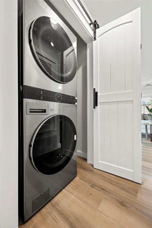 616 Bissonet Ln, Austin, TX 78752 - laundry area with stacked washer / dryer, wood finished floors, and a barn door