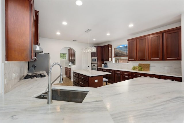 kitchen featuring a sink, appliances with stainless steel finishes, arched walkways, recessed lighting, and backsplash