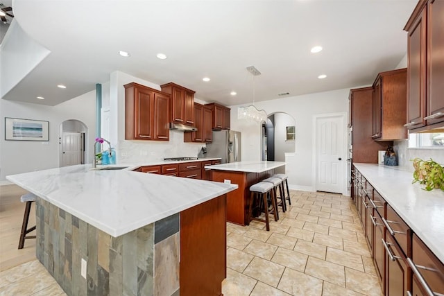 905 S Frontier Ln, Cedar Park, TX 78613 - kitchen featuring arched walkways, appliances with stainless steel finishes, a sink, a breakfast bar area, and recessed lighting