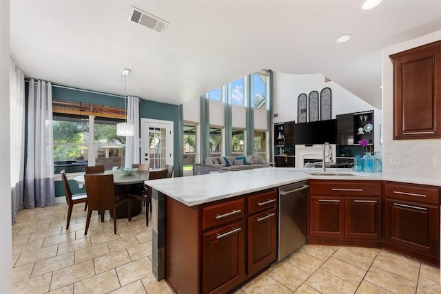 kitchen featuring a sink, dishwasher, light countertops, open floor plan, and a peninsula