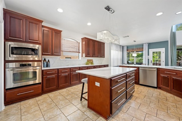 kitchen with stainless steel appliances, light countertops, a center island, recessed lighting, and decorative backsplash