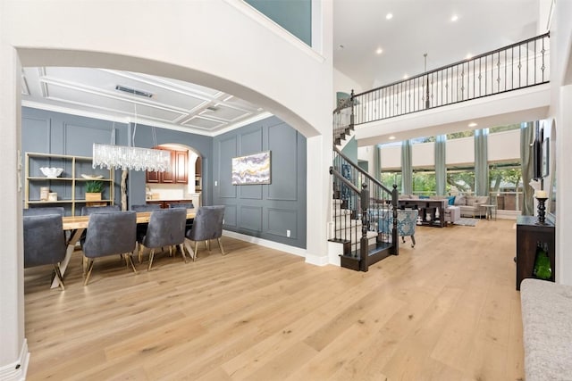 905 S Frontier Ln, Cedar Park, TX 78613 - dining room with a decorative wall, a high ceiling, arched walkways, light wood-style flooring, and stairway