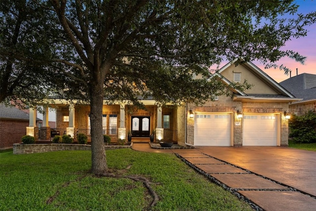 view of front of house featuring covered porch, driveway, an attached garage, a yard, and stucco siding