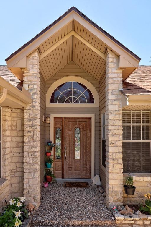 doorway to property featuring a shingled roof and stone siding
