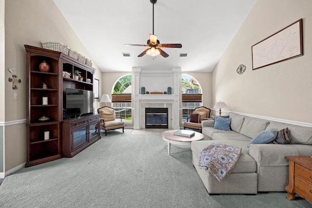 living room featuring vaulted ceiling, ceiling fan, a fireplace, and light carpet