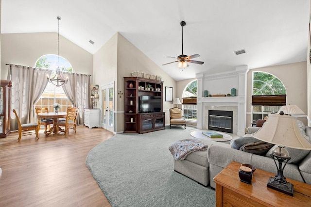living room with high vaulted ceiling, ceiling fan, a chandelier, healthy amount of natural light, and wood finished floors