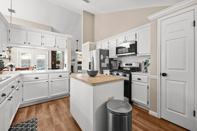 kitchen featuring stainless steel appliances, ceiling fan, light countertops, high vaulted ceiling, and white cabinets