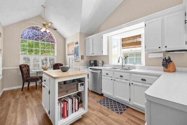 kitchen featuring dishwasher, a sink, a ceiling fan, vaulted ceiling, and light countertops