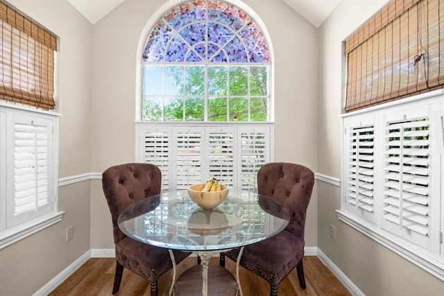 dining room featuring wood finished floors, lofted ceiling, and baseboards