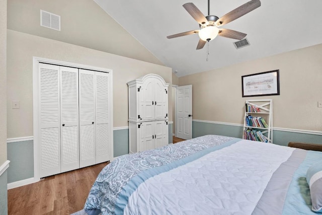 bedroom with wood finished floors, a closet, ceiling fan, baseboards, and high vaulted ceiling