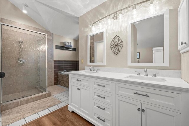 full bathroom featuring tile walls, a stall shower, lofted ceiling, and double vanity