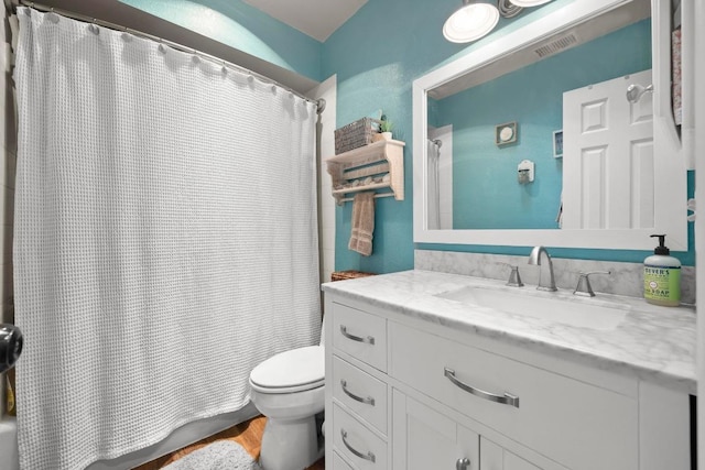 bathroom featuring toilet, shower / tub combo with curtain, vanity, and wood finished floors