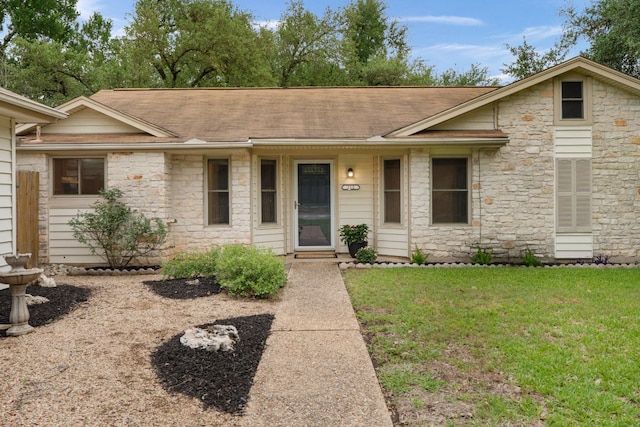 single story home featuring stone siding, a front yard, and roof with shingles