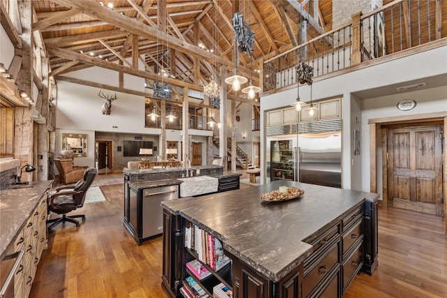 kitchen featuring appliances with stainless steel finishes, high vaulted ceiling, a center island, light wood-style floors, and open floor plan