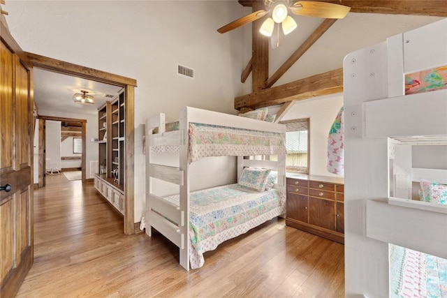 bedroom with light wood-type flooring, beamed ceiling, high vaulted ceiling, and ceiling fan