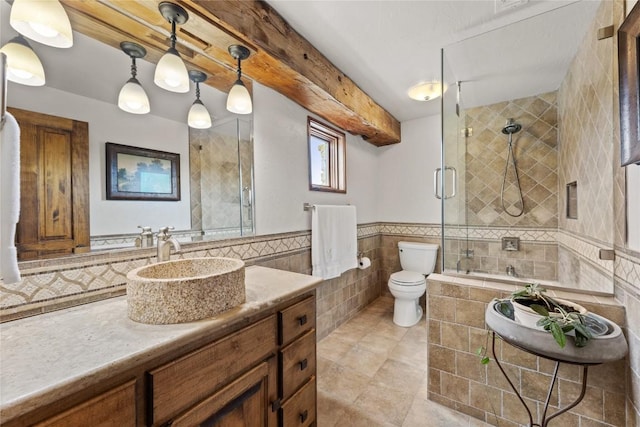 full bathroom with tile walls, tiled shower, toilet, tile patterned flooring, and vanity