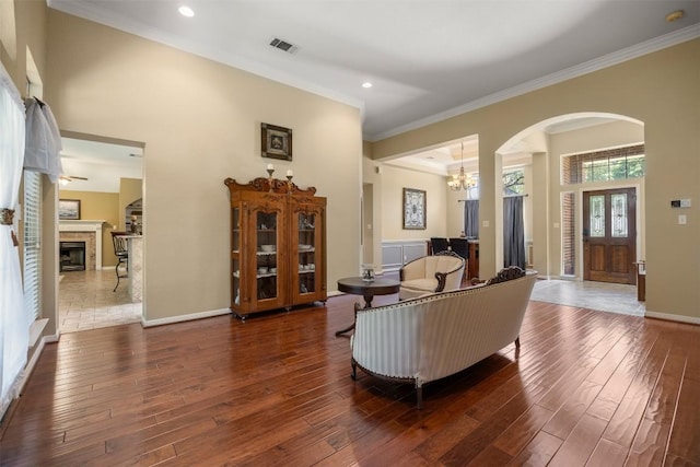 2025 Saint Andrews Dr, Round Rock, TX 78664 - living room with arched walkways, hardwood / wood-style floors, a chandelier, a fireplace, and ornamental molding