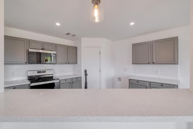 303 Flinn St, Hutto, TX 78634 - kitchen with appliances with stainless steel finishes, gray cabinets, backsplash, light countertops, and recessed lighting