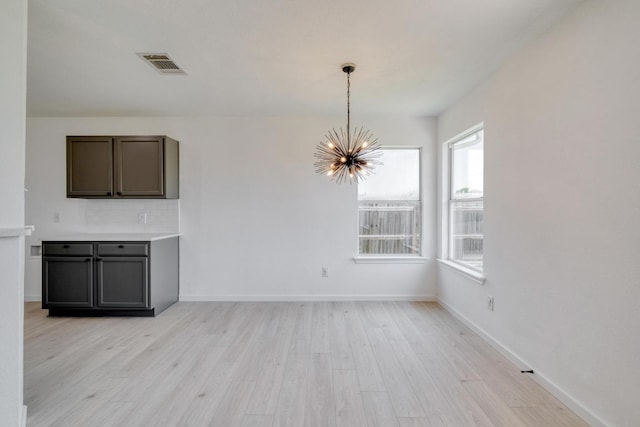 303 Flinn St, Hutto, TX 78634 - unfurnished dining area with a chandelier, light wood-style flooring, and baseboards