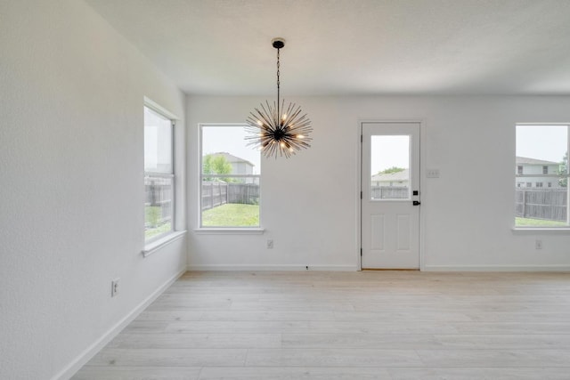 303 Flinn St, Hutto, TX 78634 - unfurnished dining area with a chandelier, light wood finished floors, and baseboards