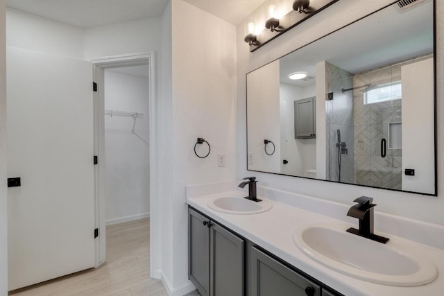 303 Flinn St, Hutto, TX 78634 - bathroom with a shower stall, double vanity, a walk in closet, and wood finished floors