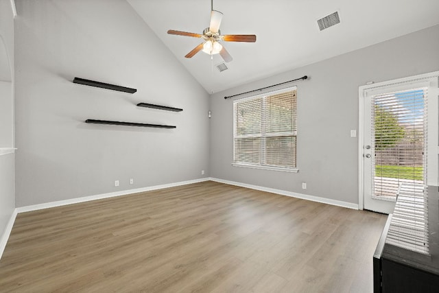 unfurnished room with plenty of natural light, a ceiling fan, wood finished floors, baseboards, and high vaulted ceiling