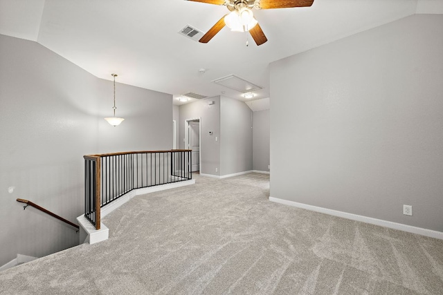 empty room featuring attic access, light colored carpet, ceiling fan, lofted ceiling, and baseboards