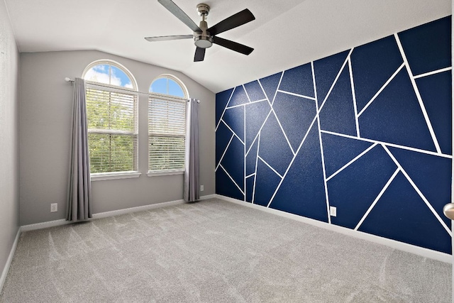 empty room with lofted ceiling, ceiling fan, carpet floors, and baseboards