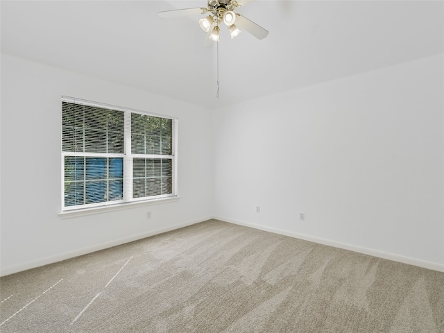 carpeted spare room featuring a ceiling fan and baseboards